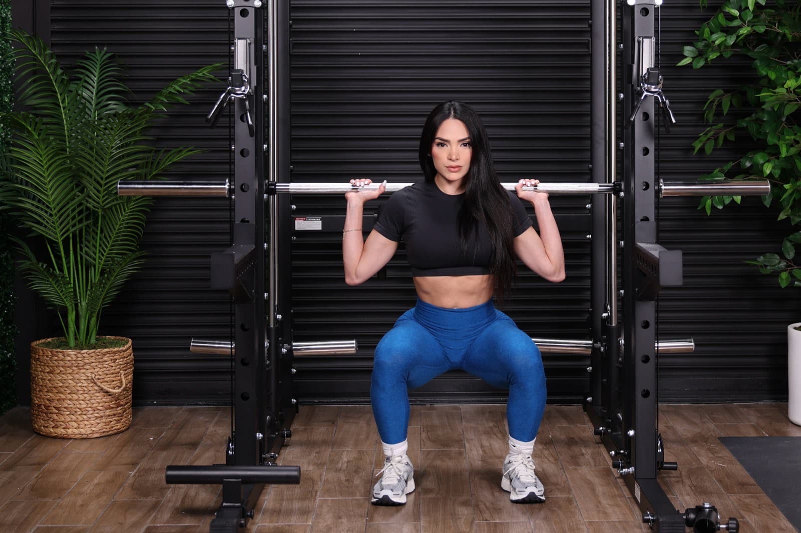Taneth squatting a barbell in a power rack
